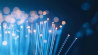 Glowing blue fiber optic cables with soft bokeh light effects against dark background create modern technology and communication concept.
