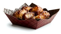 Crispy golden coconut macaroons with dark chocolate drizzle served in brown paper basket, fresh baked homemade cookies on white background for dessert menu.