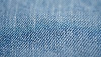 Close-up macro view of blue denim fabric texture showing detailed weave pattern and cotton fibers for fashion and textile design backgrounds.