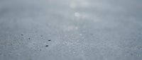 Close-up of wet asphalt surface with water droplets and bokeh effect, suitable for backgrounds, textures, and weather-related design projects.
