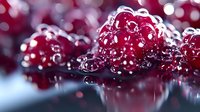 Fresh ripe red raspberries with water drops and reflection on dark surface against blurred bokeh background, macro food photography.