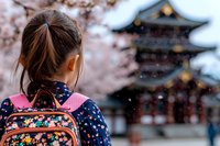Young Asian woman with backpack admiring cherry blossoms near traditional pagoda during spring season, capturing cultural tourism and wanderlust spirit.