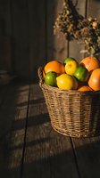 Fresh citrus fruits in wicker basket on rustic wooden table with warm sunlight and dried flowers creating cozy kitchen atmosphere for healthy eating concepts.