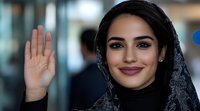 Young Middle Eastern businesswoman in hijab waving hello in modern office environment. Professional female entrepreneur greeting gesture in corporate workplace setting.