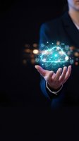 Businessman holding glowing cloud computing network with digital icons and connections floating above open palm on dark background for technology presentations.