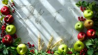 Fresh red and green apples with wheat ears and red currant berries arranged on marble background with natural sunlight and shadows. Food photography layout.