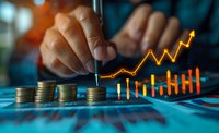 Male hands analyzing financial data with stacked coins and glowing orange growth chart on blue surface, representing investment success and market analysis.
