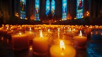 Glowing prayer candles illuminating a cathedral interior with vibrant stained glass windows creating a spiritual atmosphere of peace and remembrance.