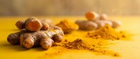 Fresh turmeric roots with golden powder spice on yellow surface for cooking, health supplements, natural medicine and culinary ingredients.