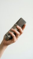 Hand holding professional condenser microphone against neutral background for recording and broadcasting applications.