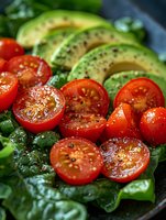 Fresh sliced cherry tomatoes and ripe avocado arranged on green spinach leaves with black pepper and seasonings, macro food photography for healthy eating.