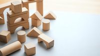 Natural wooden building blocks scattered on white surface for educational play and creative construction activities in childhood development.