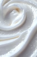 Creamy white swirls of soft whipped cream or moisturizer texture in macro close up showing smooth curves and luxurious cosmetic product background.