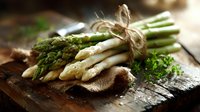 Fresh green and white asparagus spears tied with twine on rustic wooden board, selective focus with soft natural lighting and herbs for food photography.