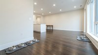 Empty modern apartment interior with hardwood flooring, white walls, recessed lighting, and large windows. Suitable for real estate, interior design, and home staging projects.