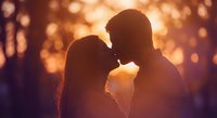Romantic couple silhouettes kissing at golden hour sunset with warm bokeh lights creating intimate atmosphere for love and relationship concepts.