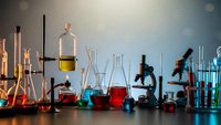 Chemistry laboratory equipment with colorful liquids in glassware, beakers, flasks and microscopes for scientific research and education experiments.