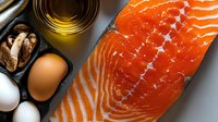 Overhead view of fresh salmon fillet with olive oil, nuts, and eggs arranged on gray surface for healthy cooking and nutrition content.