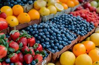 Fresh organic fruits at farmers market stall with ripe blueberries, strawberries, oranges and citrus. Colorful healthy produce display perfect for food marketing and healthy eating concept.