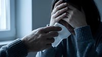 Caring person offers tissue to a crying young woman holding her head in hands, expressing grief, stress, or emotional support concept.