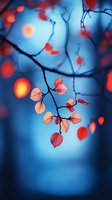 Delicate red autumn leaves on branch against dreamy blue background with soft bokeh lights creating magical forest atmosphere.