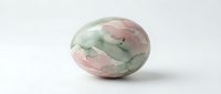 Natural prehnite gemstone with pink and green marbled patterns isolated on white background for jewelry design and mineral collection displays.