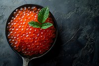 Fresh red caviar in vintage metal spoon garnished with mint leaves on dark textured background, top view. Luxurious seafood appetizer photography.