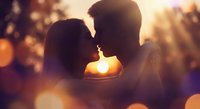 Romantic couple silhouettes kissing at golden sunset with warm bokeh lights creating intimate atmosphere for love and relationship concepts.
