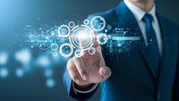 Professional businessman in dark suit touching digital interface with glowing gears and data visualization elements representing modern technology solutions.