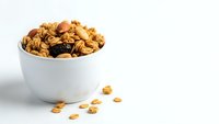 Homemade granola with nuts and dried fruits in white bowl on clean background. Healthy breakfast cereal mix for morning meal and snack recipes.