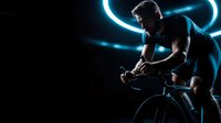 Professional cyclist in aerodynamic position on racing bike with dramatic blue neon lighting effects against dark background for sports marketing.