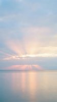 Serene ocean horizon at sunrise with soft pink and golden light rays breaking through clouds, calm water reflecting sky colors, peaceful coastal seascape for relaxation and wellness projects.