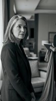 Professional mature Caucasian businesswoman in dark suit standing confidently in modern office environment, black and white corporate portrait.