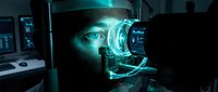 Young male technician with light skin tone examining advanced optical or robotic equipment with glowing cyan light in dark laboratory setting, suitable for technology, innovation, and engineering concepts.