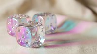 Holographic iridescent dice with rhinestone dots on neutral background for gaming and entertainment concepts.