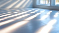 Sunlight streaming through window blinds creates dramatic shadow patterns on empty wooden floor, perfect for interior design backgrounds.