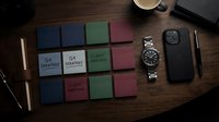 Overhead flat lay of organized workspace with colorful sticky notes, strategy planning documents, wristwatch, smartphone case, pen, and coffee cup on wooden desk surface for business productivity.