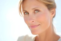 Mature blonde Caucasian woman with natural makeup and glowing skin in soft lighting for skincare and beauty advertising campaigns.