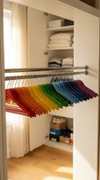 Organized closet with colorful rainbow hangers arranged by color spectrum creating vibrant storage solution for modern home organization and wardrobe management.