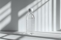 Clear plastic water bottle on white surface with dramatic window light and shadow patterns creating minimalist composition with geometric shapes.