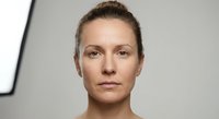 Professional middle-aged Caucasian woman with natural makeup and pulled-back hair in modern studio setting for business and healthcare concepts.