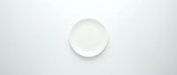Empty white ceramic plate on light gray background for food photography and kitchen design projects.