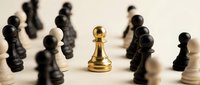 Golden pawn stands out among black and white chess pieces on wooden board, symbolizing leadership, strategy, uniqueness and competitive advantage in business.