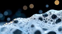 Macro close-up of soap bubbles with water droplets creating abstract foam texture against dark background with bokeh lights for cleaning concepts.