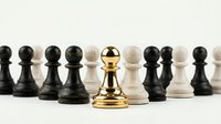 Golden chess pawn standing out among black and white pawns on light background. Leadership, strategy, success and uniqueness concept for business.