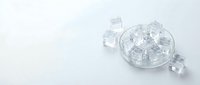 Clear ice cubes in a glass bowl with scattered cubes on white background, suitable for beverage, food and drink design projects.