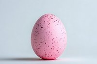 Pink speckled Easter egg with black dots on white background, isolated decorative holiday element for spring celebration designs and festive projects.