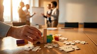 Business strategy planning with puzzle pieces on wooden table during team meeting in modern office environment for corporate problem solving.