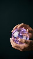 Hand holding glowing purple plasma ball with electric energy streams inside against dark background, representing innovation, technology, and future concepts for design projects.