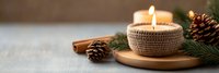 Cozy winter candle with pine cones and cinnamon sticks on wooden plate creating warm holiday atmosphere for seasonal home decor and relaxation.